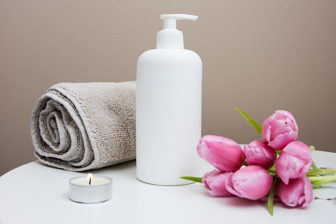 white-plastic-pump-bottle-beside-pink-tulips-and-gray-towel-vxawteiqdao